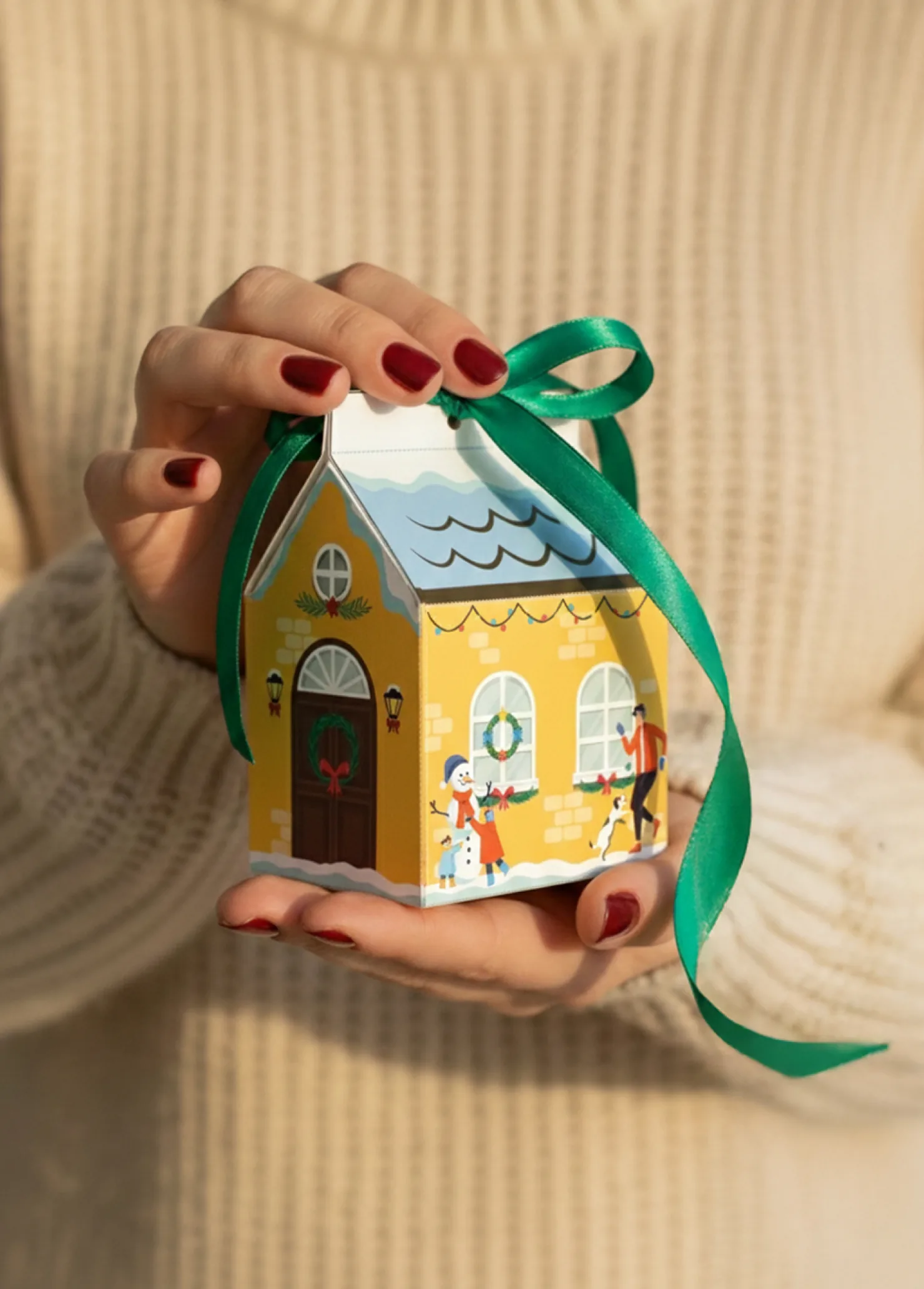 The Prozorčić gift box assembled into a yellow house and tied with a green ribbon