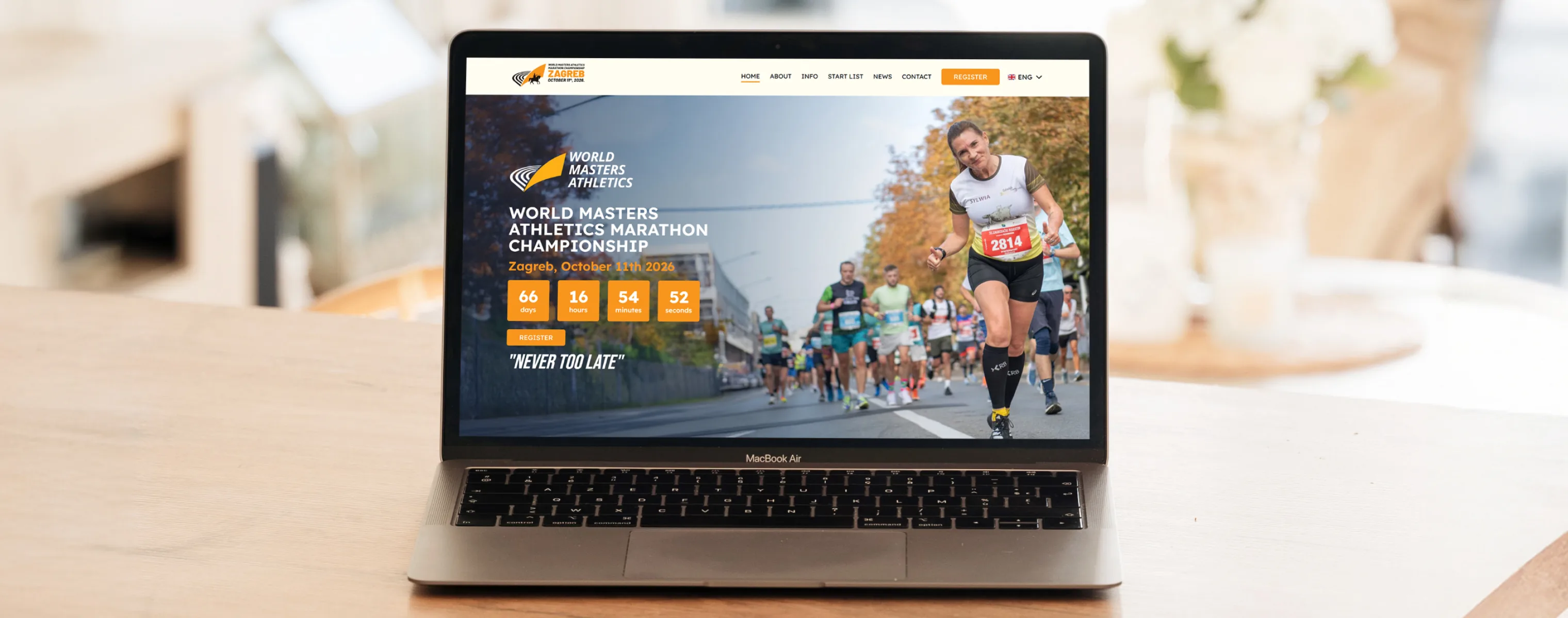 The WMAMC website on a laptop — the World Masters Athletics Marathon Championship countdown and the Never Too Late slogan